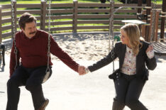 Nick Offerman as Ron Swanson and Amy Poehler as Leslie Knope holding hands on a swing in Parks and Recreation - 'One Last Ride'