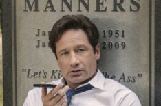 David Duchovny talking on his phone in front of the gravestone of Kim Manners in The X-Files