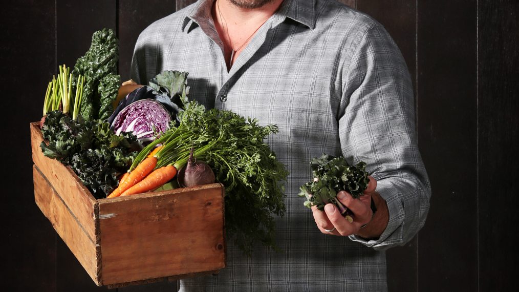 Chef Curtis Stone holds a wooden box filled with winter vegetables and kalettes during a photo shoot in Sydney