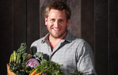 Chef Curtis Stone holds a wooden box filled with winter vegetables and kalettes during a photo shoot in Sydney