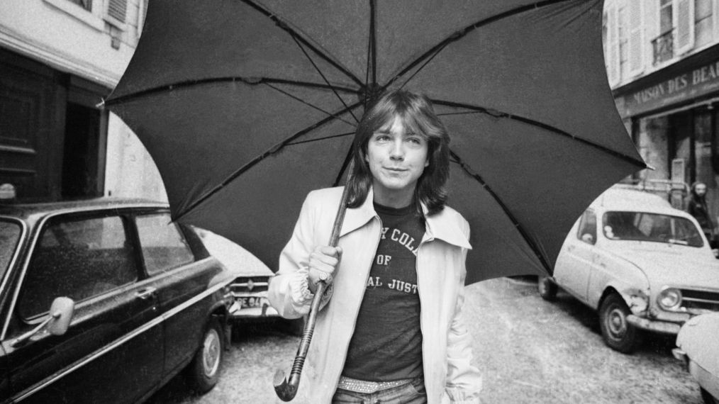 David Cassidy walking down a road in Paris with an umbrella in April 1974