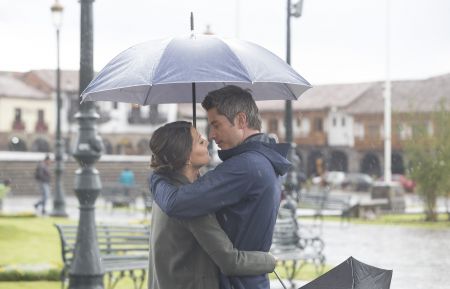 Becca Kufrin and Arie Luyendyk Jr. in the rain with an umbrella