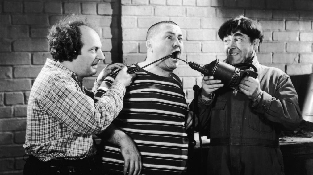 Larry Fine and Moe Howard abuse Curly Howard with tools in a still from the Three Stooges