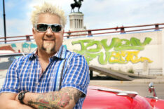 Guy Fieri in front of a shiny red car and wall covered in graffiti near El Figaro in Havana, Cuba as seen on Food Network's Diners, Drive-Ins, and Dives