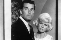 James Garner and Doris Day stand in doorway looking into room in a scene from the film 'Move Over, Darling'