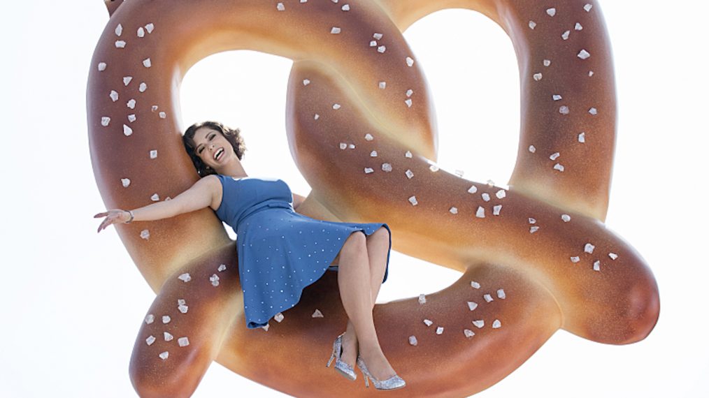 Rachel Bloom as Rebecca Bunch on a giant pretzel in the pilot of Crazy Ex-Girlfriend