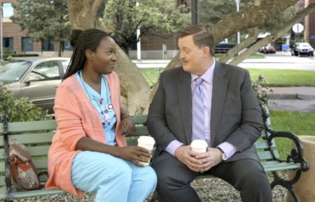 Folake Olowofoyeku and Billy Gardell sitting on a park bench in Bob Hearts Abishola