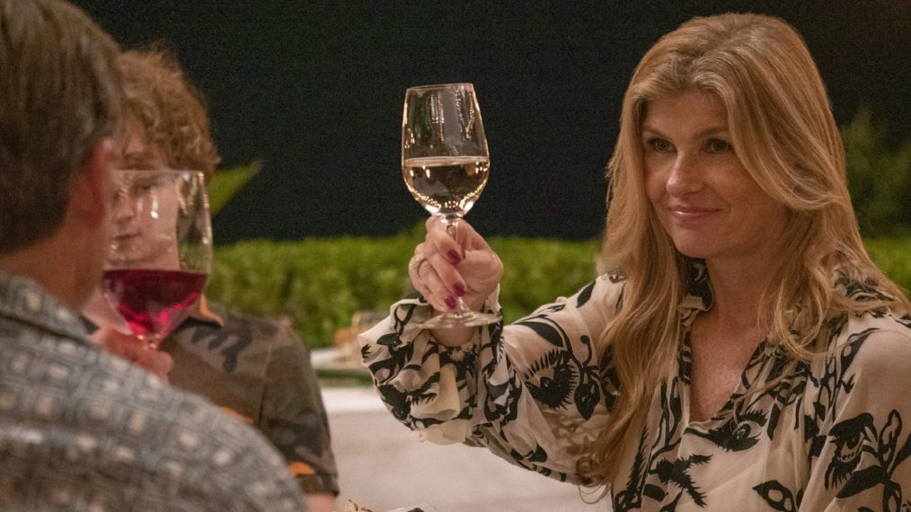 Connie Britton holding up a glass of white wine in The White Lotus