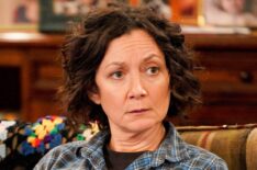 Sara Gilbert sitting on the couch in The Conners