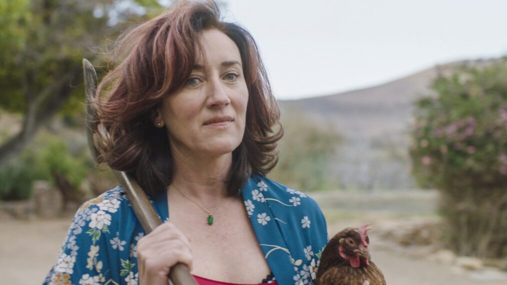 Maria Doyle Kennedy with a rooster and axe in Recipes for Love and Murder