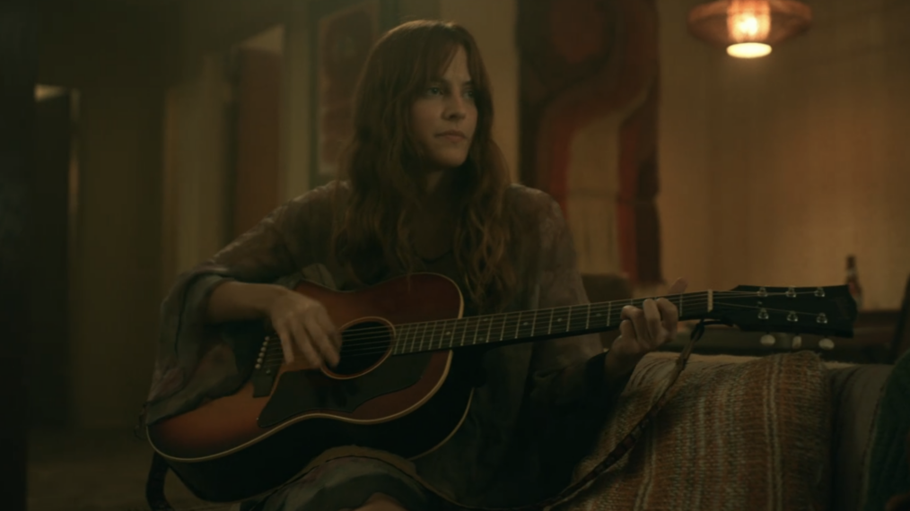 Riley Keough playing a guitar
