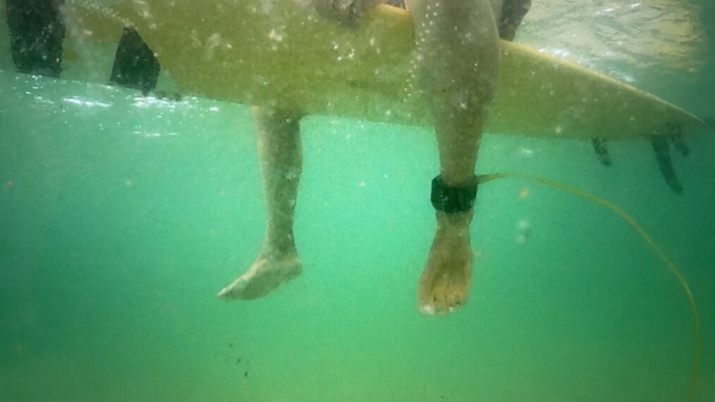 Feet dangling off of a surfboard underwater in 'After the Bite' on HBO