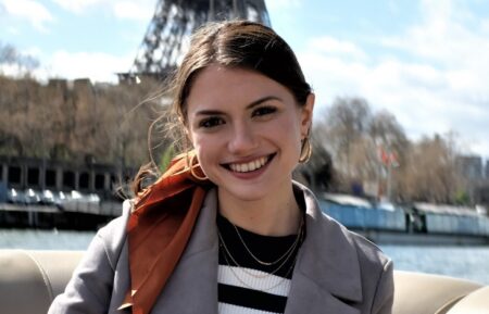 Shifra Zuckerman as Lucy arriving in Paris and posing by the Eiffel Tower