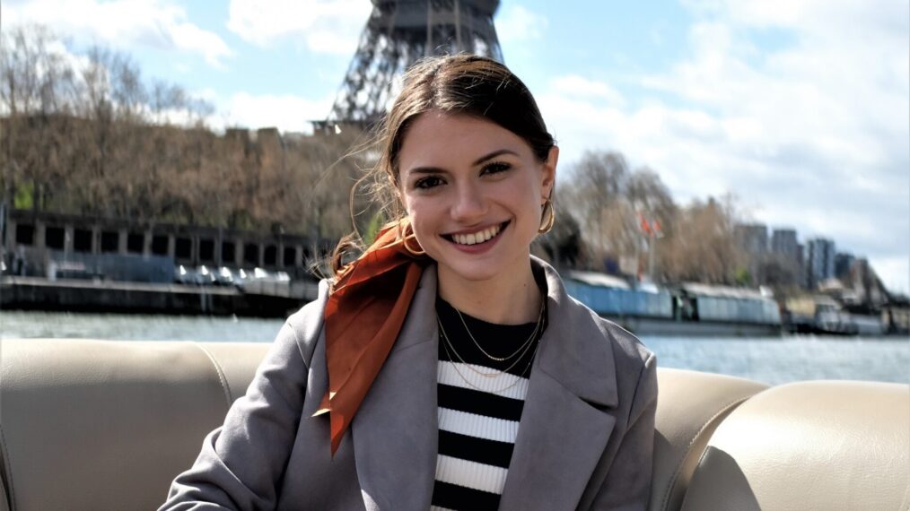 Shifra Zuckerman as Lucy arriving in Paris and posing by the Eiffel Tower