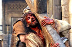 Jim Caviezel carrying a cross in the streets in The Passion of The Christ