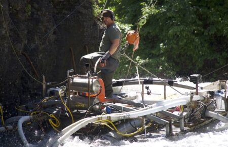 Dustin Hurt standing on the 'Deuce Sluice' overlooking the two divers in the water