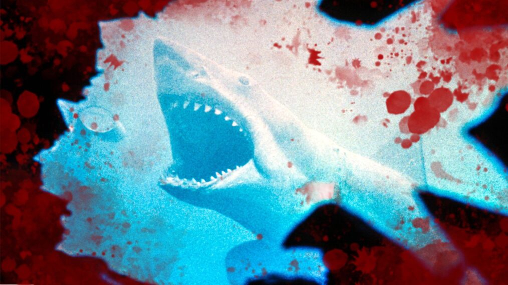 photo illustration based off the 1975 movie 'Jaws,' included with an article about scenes deleted from the movie for being too violence. The Image is centered by the large great white shark seen underwater, with its mouth widely agape and aimed toward the surface. Around this image, juxtaposed with the blue water, is red smears and blood spots.