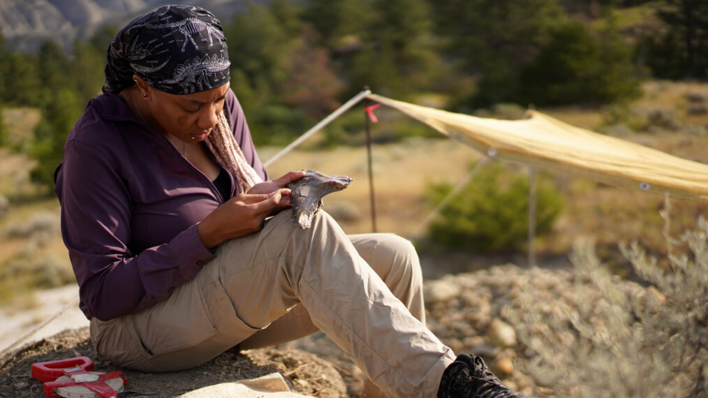 Fossil restorer Nikki Simon sits at dig site examining a Triceratops jawbone in 'Walking With Dinosaurs' on PBS