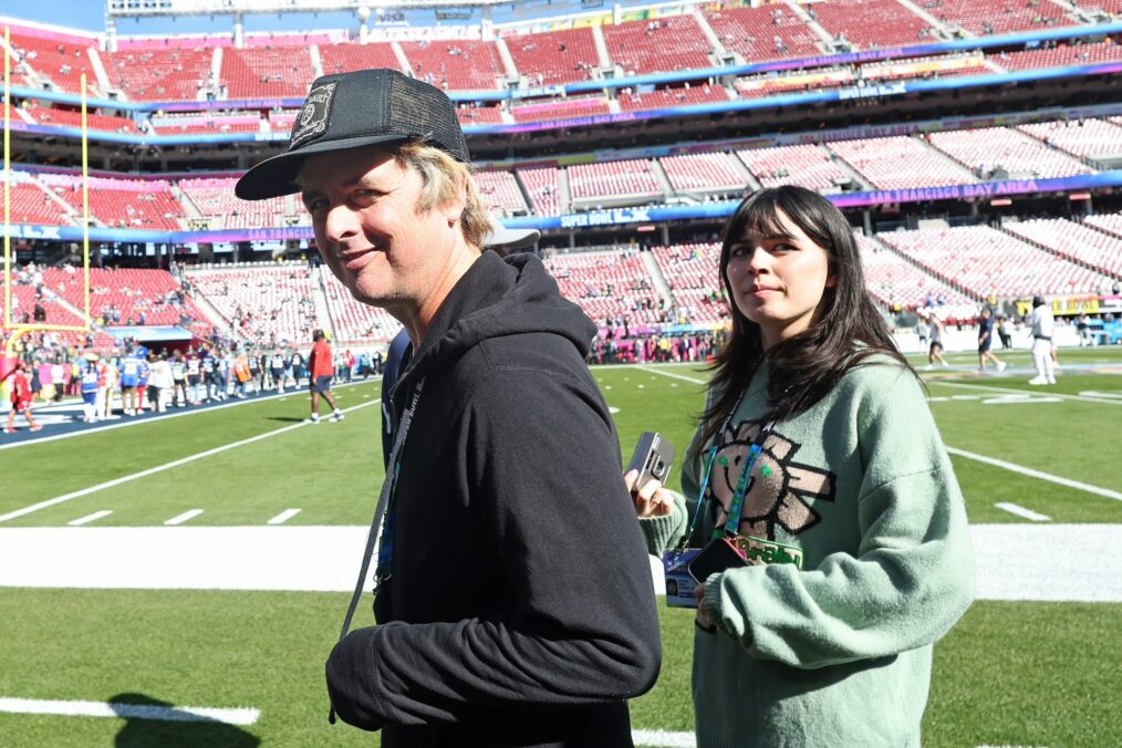 Billie Joe Armstrong (L) of Green Day looks on from the field before Super Bowl LX between the Seattle Seahawks and the New England Patriots