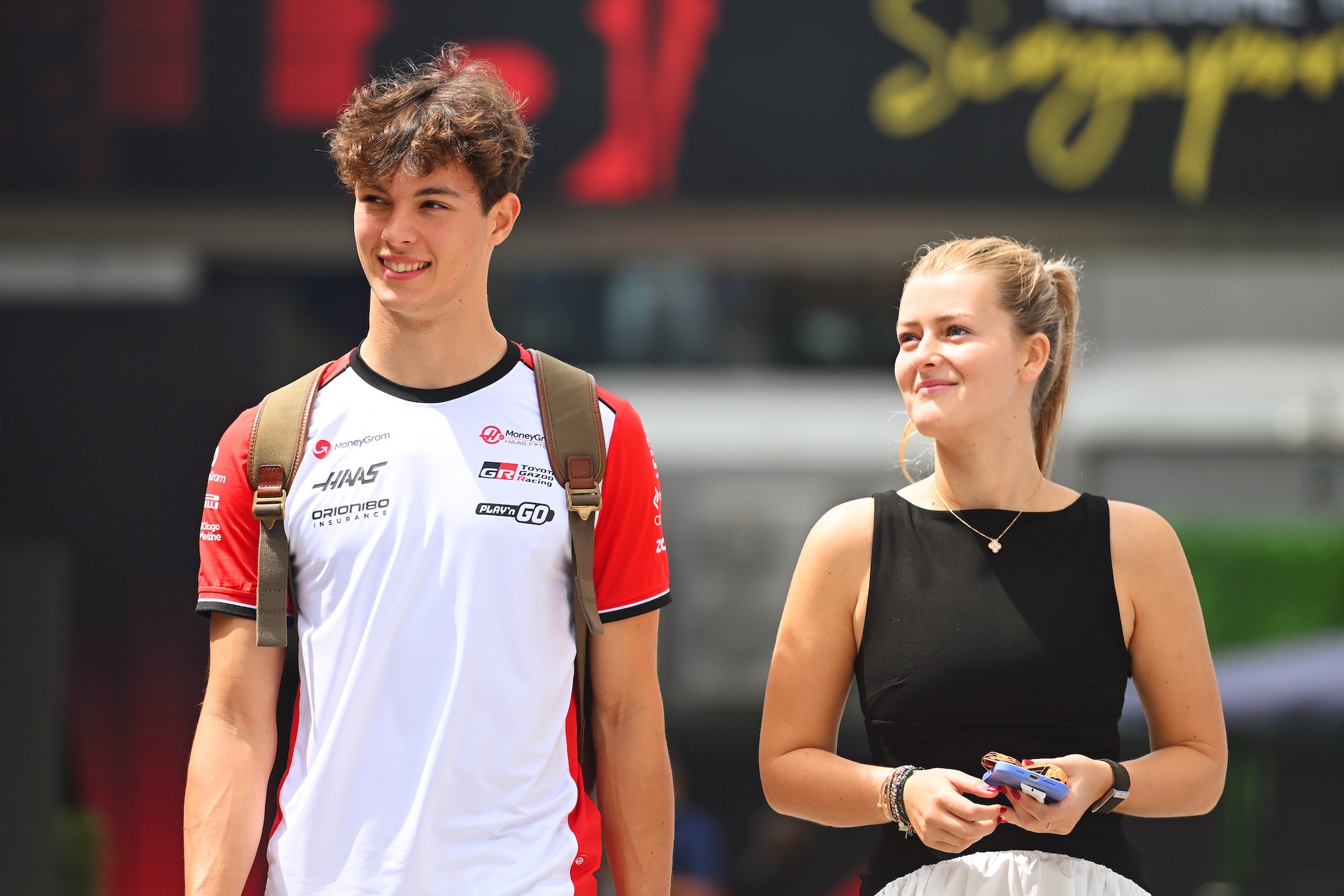 Oliver Bearman of Great Britain and Haas F1 and Alicia Stent-Torriani arrive in the Paddock prior to final practice ahead of the F1 Grand Prix of Singapore at Marina Bay Street Circuit on October 04, 2025 in Singapore, Singapore.