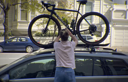 A photo of Moriah Wilson securing a bicycle on the roof of a car, as seen in the Netflix documentary 'The Truth and Tragedy of Moriah Wilson'
