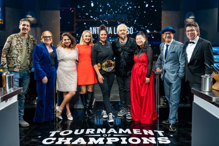 Host Guy Fieri and winning contestant Antonia Lofaso with Hunter Fieri, Tiffani Faison, Maneet Chauhan, Brooke Williamson, Mei Lin, Simon Majumdar, and Justin Warner, as seen on Tournament of Champions, Season 6, Food Network, 2025.