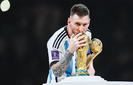 LUSAIL CITY, QATAR - DECEMBER 18: Lionel Messi of Argentina kisses the FIFA World Cup Qatar 2022 Winners' Trophy while holding the adidas Golden Boot award after the FIFA World Cup Qatar 2022 Final match between Argentina and France at Lusail Stadium on December 18, 2022 in Lusail City, Qatar.