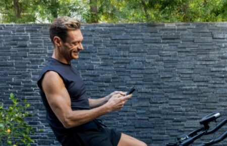 Ryan Seacrest exercising on a stationary bike at his home