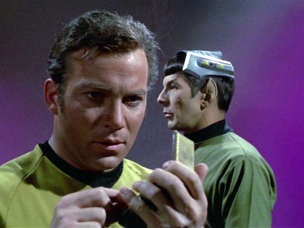 William Shatner as Captain James T. Kirk speaks into his communicator with Leonard Nimoy as Mr. Spock in the background in 'Star Trek' Season 3 Episode 1, 'Spock's Brain'