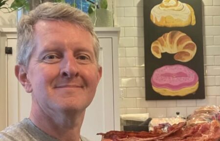 Ken Jennings standing next to a pile of 100 pieces of bacon
